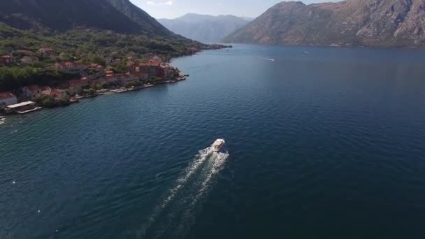 El barco del placer navega a lo largo de la bahía de Kotor más allá de la costa de la ciudad de Prcanj — Vídeos de Stock