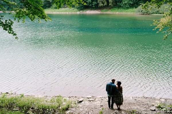 Hombre y mujer de pie en la orilla de un lago en el parque. Vista trasera —  Fotos de Stock