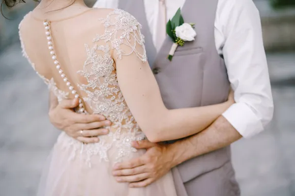 Mains de marié sur la taille de la mariée dans une robe en dentelle brodée. Gros plan — Photo