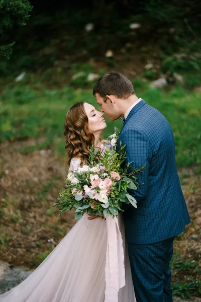 Sposa con un bouquet quasi bacia lo sposo in giardino — Foto Stock