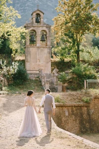 Groom and bride go to a small chapel in the garden of an old villa — Stock Photo, Image