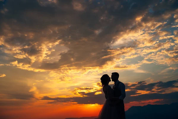 Noivo abraços noiva no fundo do pôr do sol — Fotografia de Stock