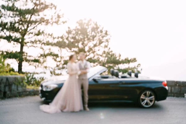 Braut und Bräutigam stehen neben dem Cabrio auf der Straße. Unschärfe — Stockfoto
