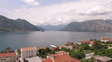 Dağların arasında deniz kıyısındaki kasabanın insansız hava aracı görüntüsü.