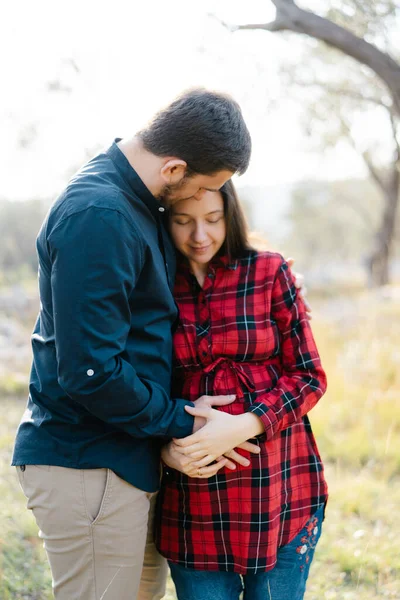 Man hugs a pregnant woman while holding his hand on her belly — Stock Photo, Image