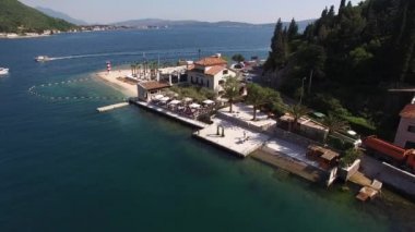 Kumlu sahil, güneşli şezlonglar, palmiyeler ve evleri olan Hırvat kıyıları