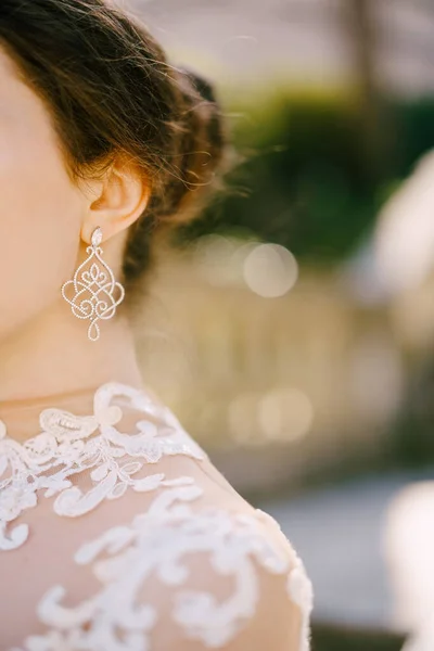 Prachtige open werk kostbare oorbel in het oor van de bruid in een witte jurk. Close-up — Stockfoto
