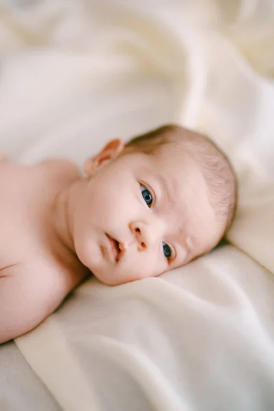 Egy újszülött arca fekszik egy bézs takarón. Közelkép — Stock Fotó