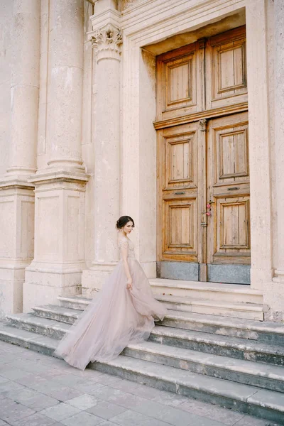 Nevěsta stojí na schodech před dřevěnými dveřmi starobylé budovy — Stock fotografie