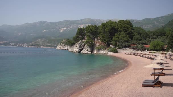 Aman beach with sun loungers by the sea on Sveti Stefan island, Montenegro — Stock Video