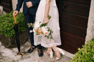 Gelin ve damat eski bir taş evin kapısında dikiliyorlar. Yakın plan.