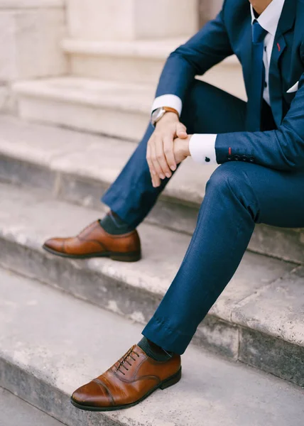 Man in a blue suit sits on the stone steps. Close-up — Stock Photo, Image