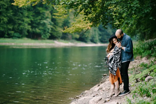 L'uomo abbraccia una donna incinta vicino al lago — Foto Stock