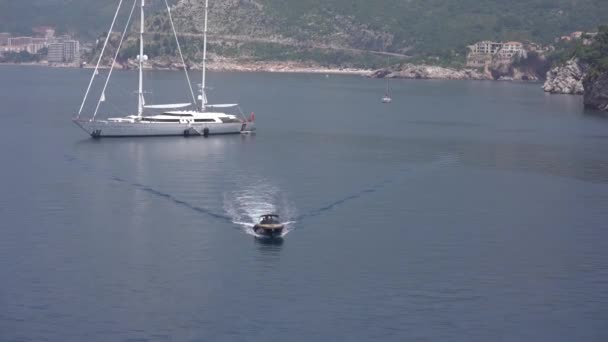 Barco a motor navega a la orilla desde un yate blanco de lujo — Vídeos de Stock