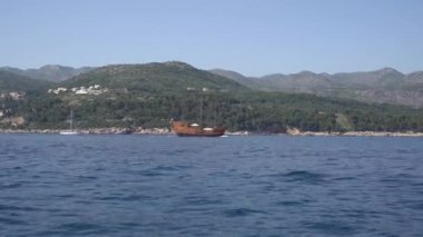 Denizde ahşap yelkenli gemi yeşil dağların arka planına karşı