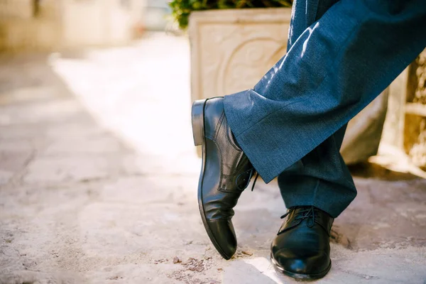 Pés masculinos de sapatos pretos e calças azuis no chão de pedra. Close-up — Fotografia de Stock