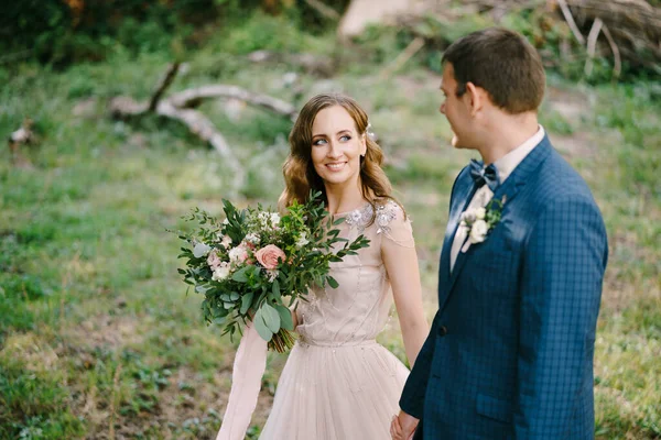 Marié souriant regardant mariée avec bouquet dans le jardin — Photo