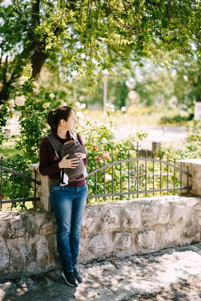 石の柵の上に寄りかかって立っている赤ん坊を持つお母さん — ストック写真