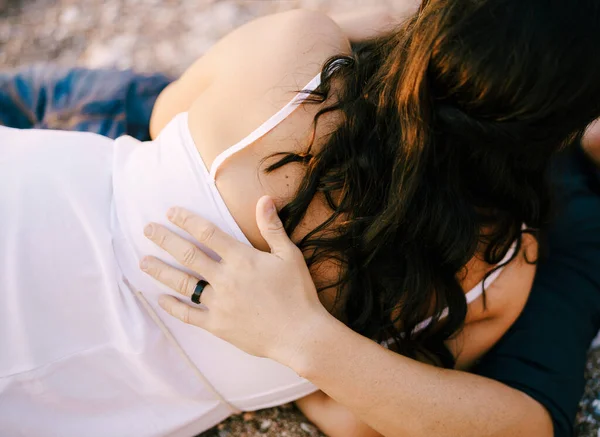 Homem e mulher abraçando enquanto deitados no caminho de cascalho no parque — Fotografia de Stock