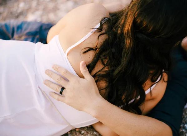 Man and woman hugging while lying on the gravel path in the park — Stock Photo, Image