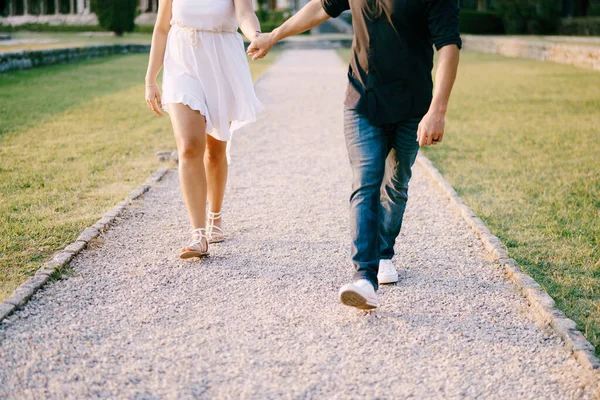 Férfi és nő sétálnak a kavicsos ösvényen a parkban kéz a kézben — Stock Fotó