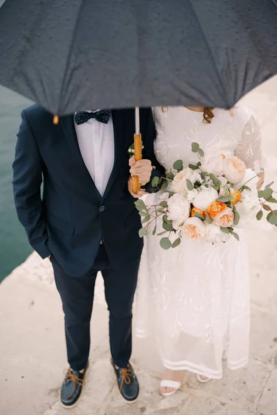 A menyasszony és a vőlegény a mólón állnak egy esernyő alatt. Közelkép — Stock Fotó
