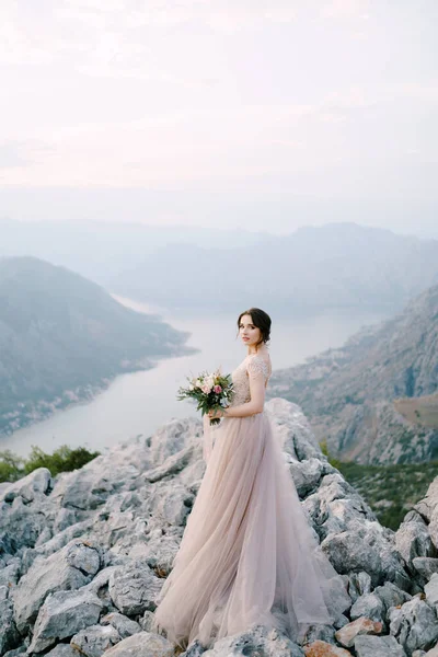 Noiva fica em uma montanha rochosa contra o pano de fundo da Baía Kotor — Fotografia de Stock