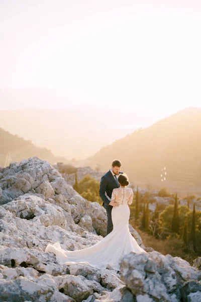 Nevěsta a ženich objímají na vrcholu hory — Stock fotografie