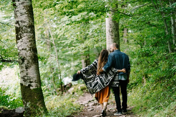 Um homem e uma mulher num abraço estão a caminhar num parque verde. Visão traseira — Fotografia de Stock