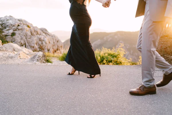 男と妊婦は山のアスファルトの道路に沿って歩いている。閉鎖 — ストック写真