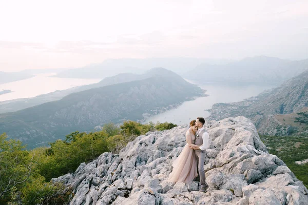 Bräutigam umarmt Braut auf dem Berg vor dem Hintergrund der Bucht von Kotor. Drohne — Stockfoto