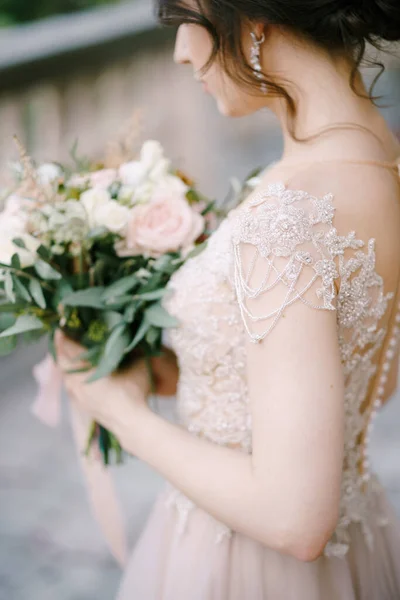 Bruid in een kanten jurk met een boeket bloemen. Zijaanzicht. Close-up — Stockfoto