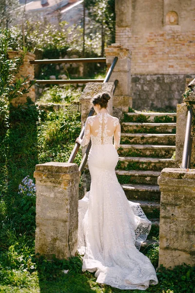 Menyasszony fehér sellő ruhában felmászik a lépcsőn a régi kápolnába. — Stock Fotó