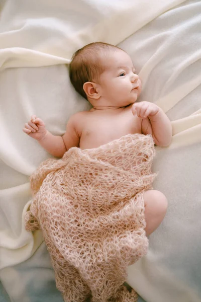 Newborn lies on the bed, covered with a shawl — Stock Photo, Image