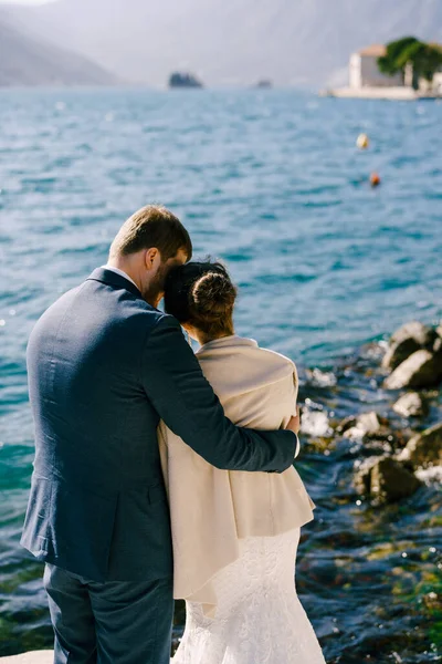 Nevěsta a ženich se objímají na břehu zátoky. Zadní pohled — Stock fotografie