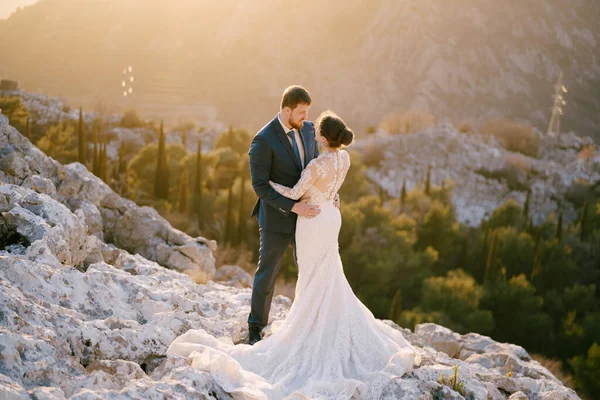 Nevěsta a ženich objímají na skalnaté hoře — Stock fotografie