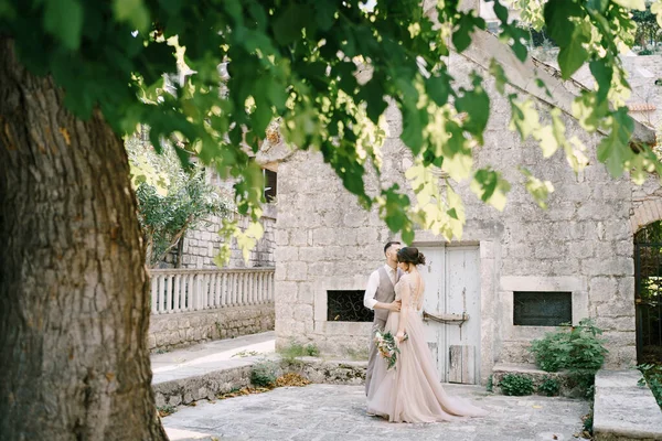 Noiva e noivo abraçando perto de um edifício de pedra — Fotografia de Stock