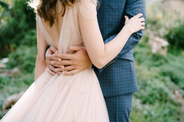 Damat, gelin beline sarılır. Yakın plan.