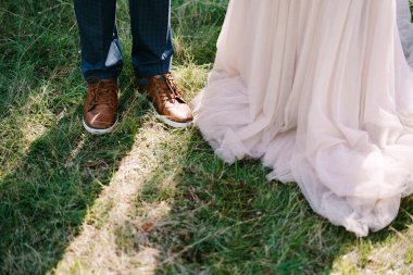 Gelin ve damat yeşil çimlerin üzerinde duruyor. Yakın plan.