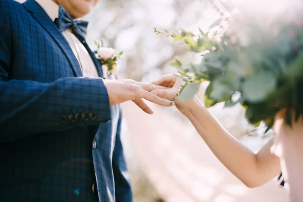 La mariée met la bague sur le doigt du marié dans le parc. Gros plan — Photo