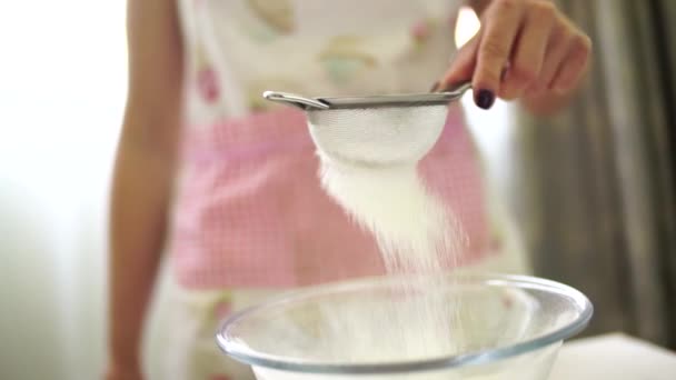 Kvinna sållar mjöl genom en såll till en skål — Stockvideo
