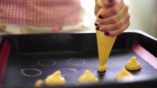 Vrouw hand knijpt het taartdeeg op een bakplaat uit een banketzak — Stockvideo