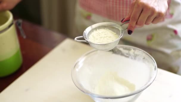 Szef kuchni przesiewa mąkę przez małe sito do miski na stole — Wideo stockowe