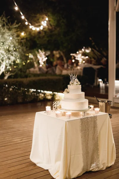 Pastel de boda de tres niveles decorado con flores en una mesa con un mantel — Foto de Stock