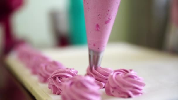 Szef wyciska różowe jagodowe pianki w rzędzie z torby ciasta — Wideo stockowe