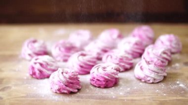 Masadaki bitmiş pembe şekerin üzerine ince bir tabaka pudra şekeri serpiyorum.