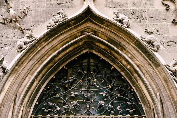 Kovová oblouková mříž z tepaného železa nad dveřmi na staré fasádě se štukovou výplní — Stock fotografie