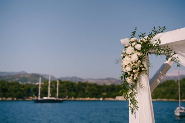 Denizin ve dağların zeminine güllerle süslenmiş bir düğün örtüsü parçası.