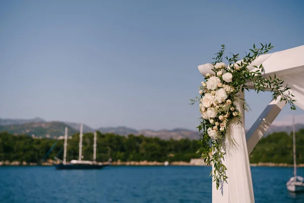 Fragmento de un dosel de boda decorado con rosas en el fondo del mar y las montañas — Foto de Stock