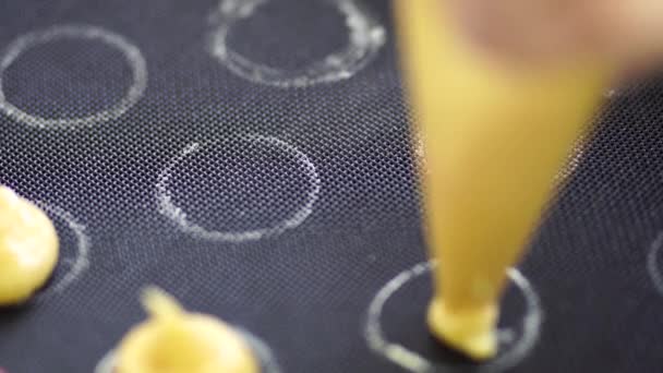 Pasticcere spreme choux au craquelin da una borsa da pasticceria su un tappeto di silicone — Video Stock